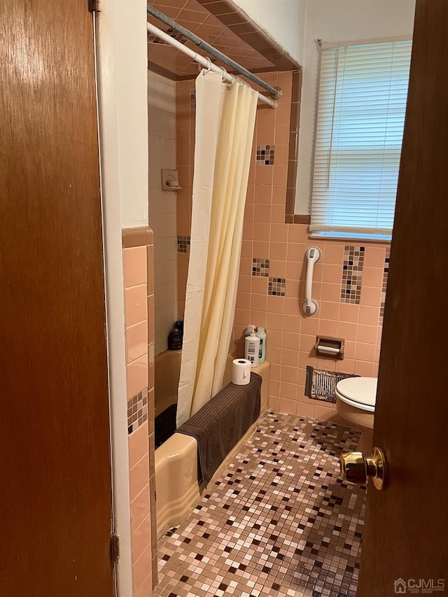 bathroom featuring shower / tub combo with curtain, tile patterned flooring, toilet, and tile walls