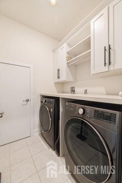 20 Metro Dr, Monroe, NJ 08831 - laundry area with washer and clothes dryer, cabinet space, light tile patterned floors, and baseboards