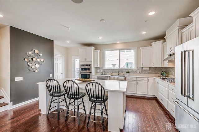 kitchen with a kitchen island, sink, white cabinets, and appliances with stainless steel finishes