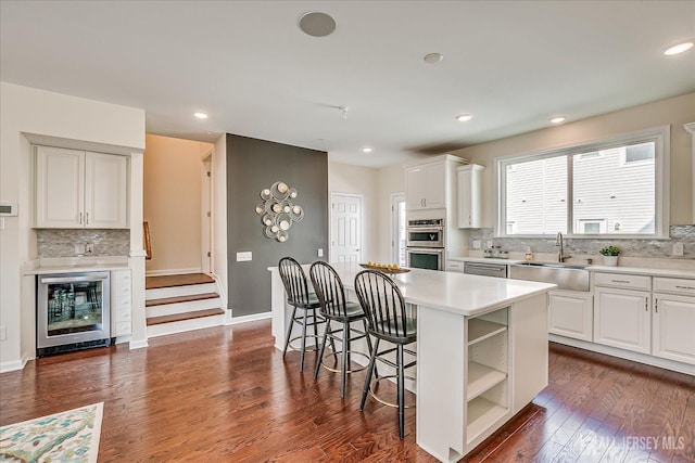 kitchen featuring a kitchen island, sink, white cabinets, and a breakfast bar