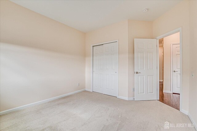 unfurnished bedroom with light carpet and a closet