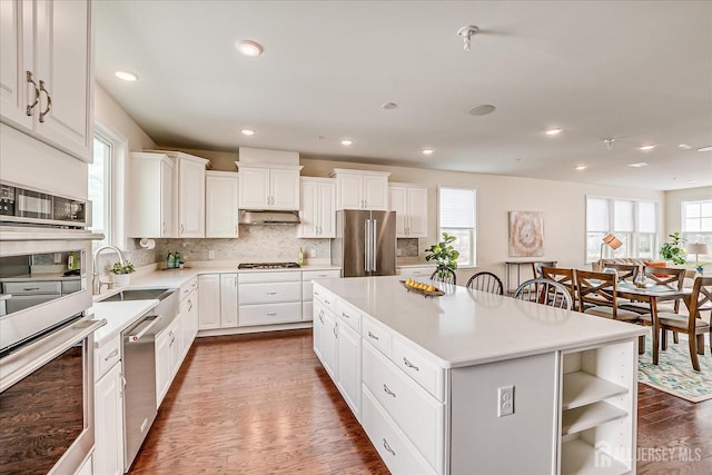 kitchen featuring sink, white cabinetry, stainless steel appliances, dark hardwood / wood-style floors, and a center island