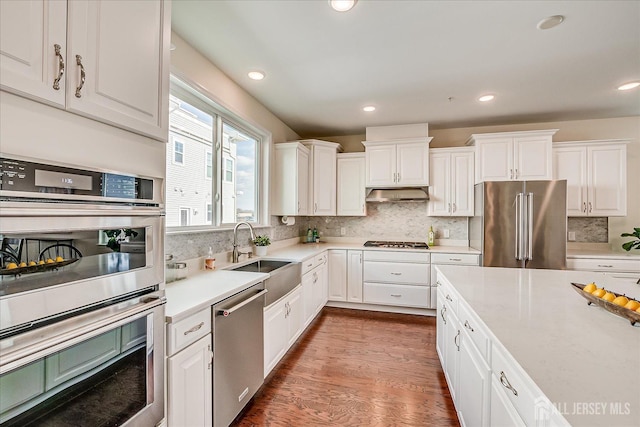 kitchen featuring appliances with stainless steel finishes, tasteful backsplash, white cabinetry, sink, and dark wood-type flooring