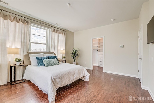 bedroom with wood-type flooring and a spacious closet