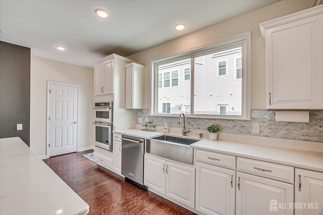 kitchen featuring sink, backsplash, stainless steel appliances, dark hardwood / wood-style floors, and white cabinets