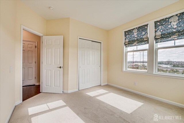 unfurnished bedroom with light carpet and a closet