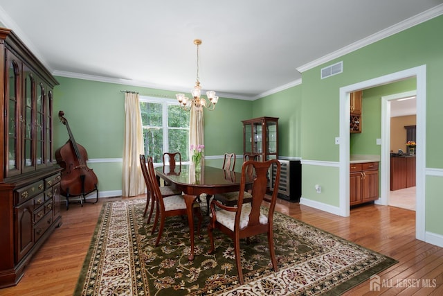3 Wheatsheaf Ct, Plainsboro, NJ 08536 - dining area featuring light wood-style flooring, a chandelier, ornamental molding, and beverage cooler