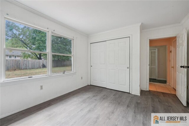 unfurnished bedroom with dark hardwood / wood-style flooring, a closet, and crown molding