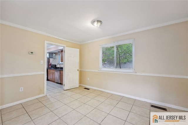 empty room featuring light tile patterned floors, ornamental molding, and sink