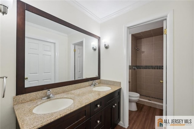 bathroom featuring crown molding, a sink, a shower stall, and wood finished floors