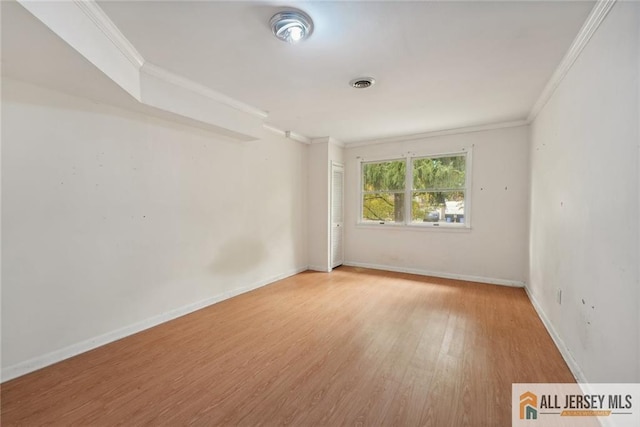 spare room featuring ornamental molding, wood finished floors, visible vents, and baseboards