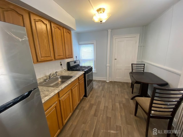 kitchen with stainless steel appliances, light stone counters, sink, tasteful backsplash, and dark hardwood / wood-style floors