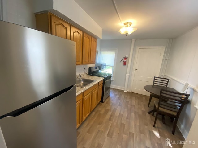 kitchen with stainless steel appliances, light hardwood / wood-style floors, and sink