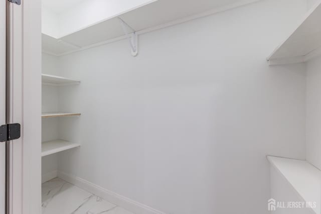 walk in closet with marble finish floor