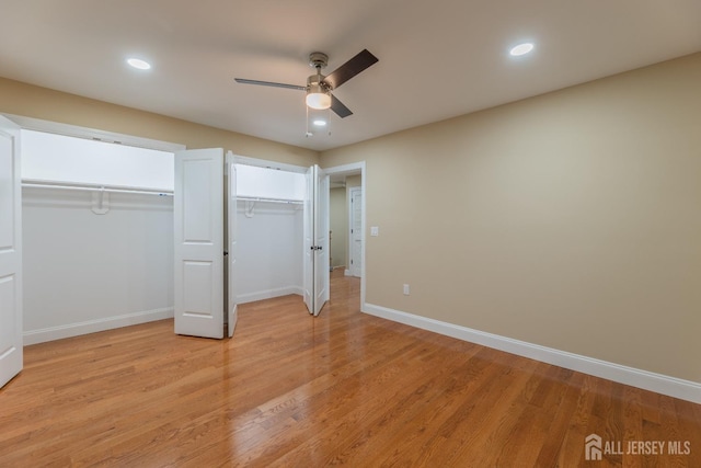 unfurnished bedroom with baseboards, recessed lighting, light wood-type flooring, and multiple closets