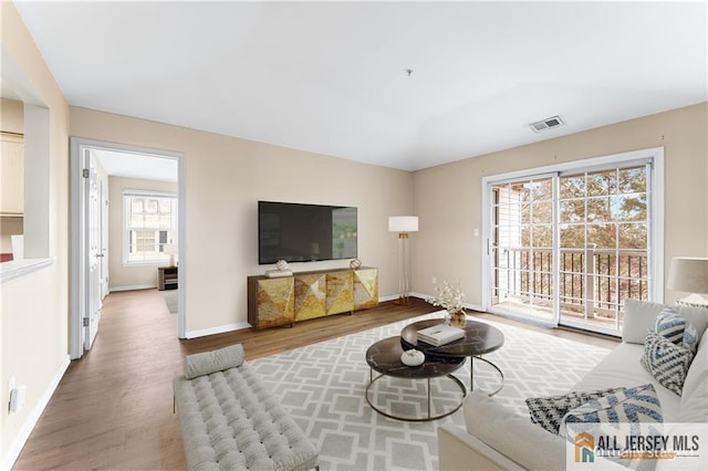 living room featuring wood finished floors, visible vents, and baseboards