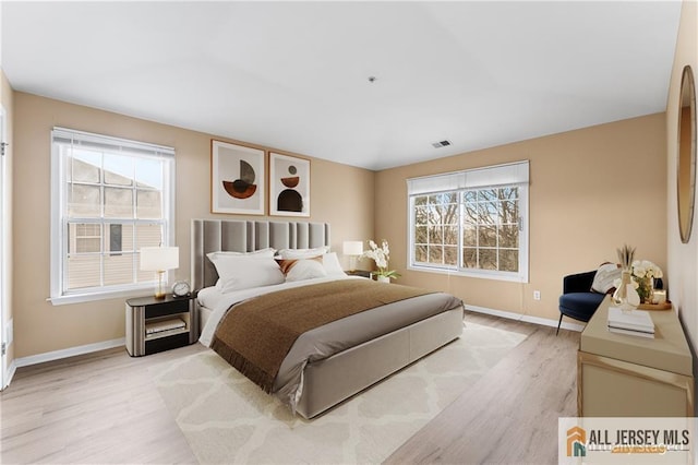 bedroom with light wood finished floors, visible vents, and baseboards