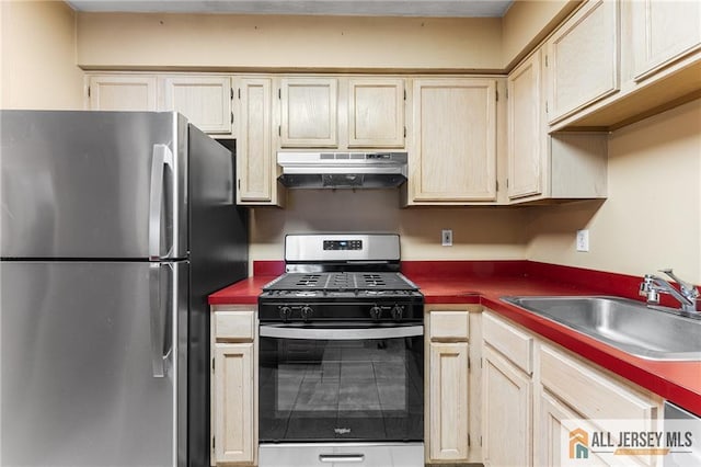 kitchen with stainless steel appliances, dark countertops, a sink, and under cabinet range hood