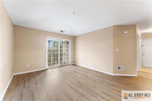 empty room with visible vents, baseboards, and wood finished floors