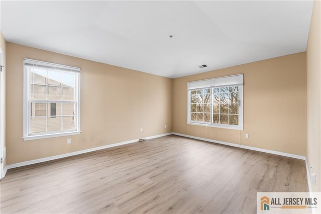 unfurnished room featuring a wealth of natural light and baseboards