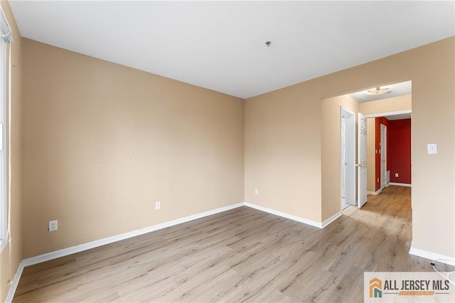 unfurnished room with light wood-type flooring and baseboards