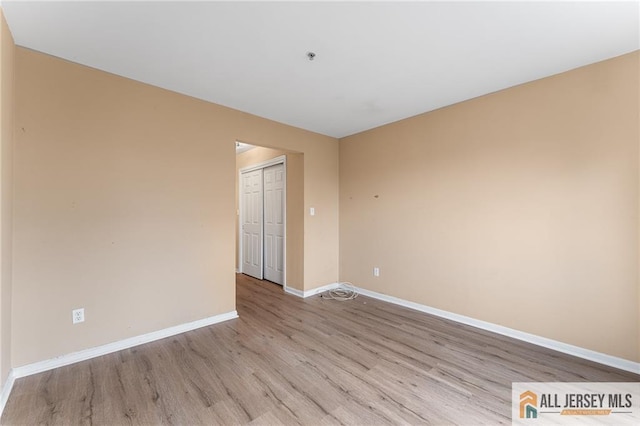 unfurnished room with light wood-style flooring and baseboards