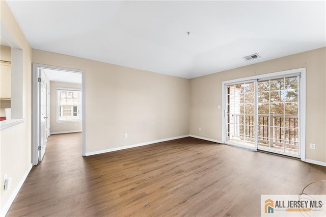 unfurnished room with baseboards, visible vents, and wood finished floors