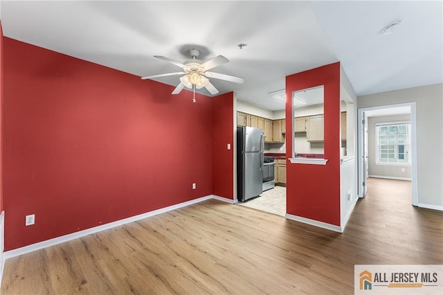 kitchen featuring ceiling fan, stove, baseboards, light wood-type flooring, and freestanding refrigerator