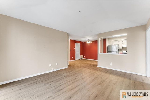 unfurnished living room featuring visible vents, a ceiling fan, light wood-style flooring, and baseboards