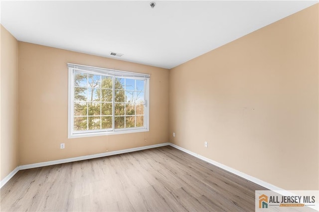 empty room with baseboards, visible vents, and wood finished floors