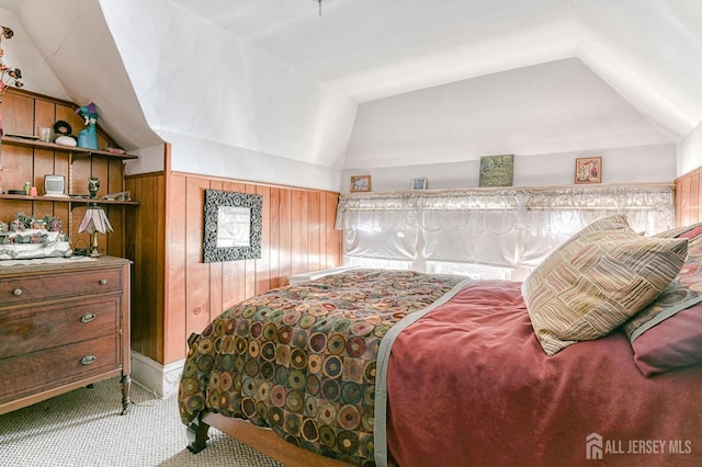 carpeted bedroom with wood walls and lofted ceiling