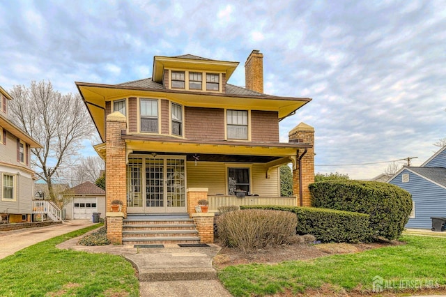 american foursquare style home with an outdoor structure, a chimney, a detached garage, brick siding, and covered porch
