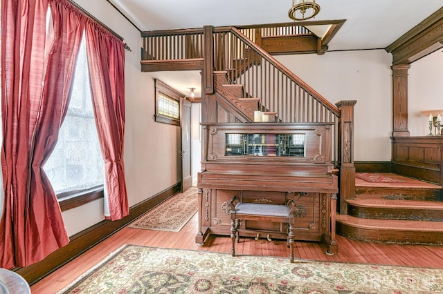 staircase featuring baseboards, wood finished floors, and a healthy amount of sunlight