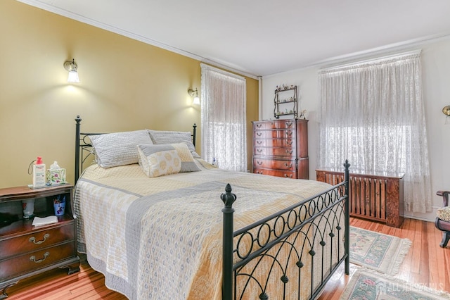 bedroom with ornamental molding and wood finished floors