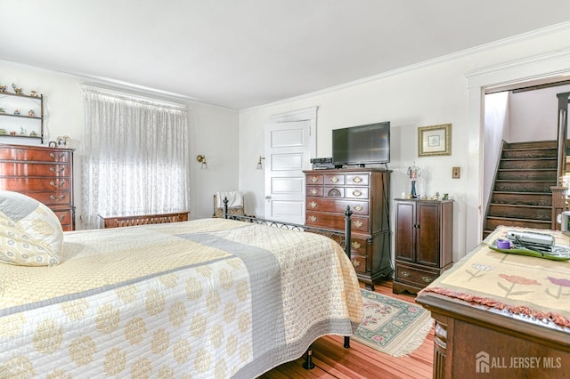 bedroom with ornamental molding, a closet, and wood finished floors