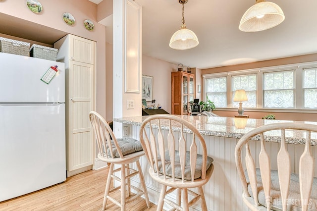 5 Llewellyn Pl, New Brunswick, NJ 08901 - kitchen with freestanding refrigerator, light wood-style floors, a kitchen bar, hanging light fixtures, and light stone counters