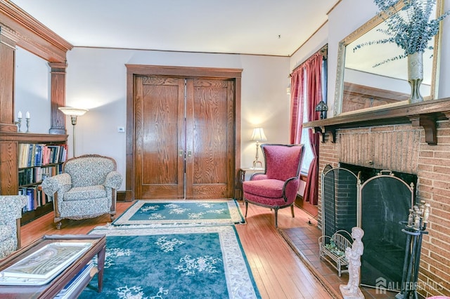 living area with a brick fireplace and hardwood / wood-style flooring