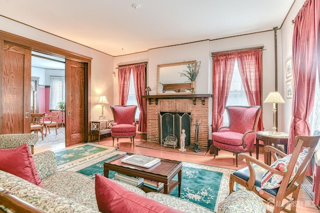 living area with a healthy amount of sunlight, wood finished floors, and a brick fireplace