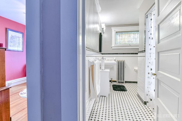 bathroom with tile patterned floors, tile walls, and radiator