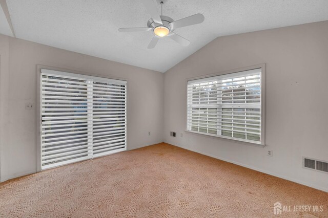 carpeted empty room with a textured ceiling, ceiling fan, and lofted ceiling