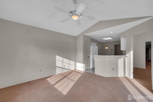 carpeted empty room featuring a textured ceiling, ceiling fan, and lofted ceiling