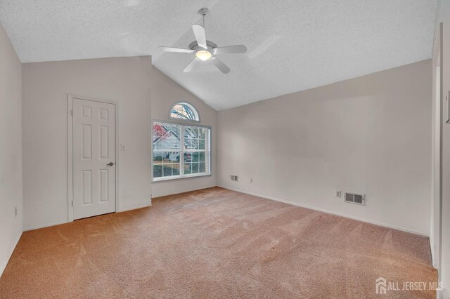 unfurnished room featuring a textured ceiling, ceiling fan, lofted ceiling, and light carpet