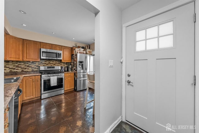 1058 Schmidt Ln, North Brunswick, NJ 08902 - kitchen with stainless steel appliances, tasteful backsplash, dark tile patterned flooring, brown cabinetry, and baseboards