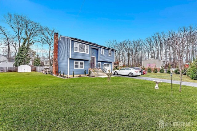 split foyer home featuring a front yard and a storage shed