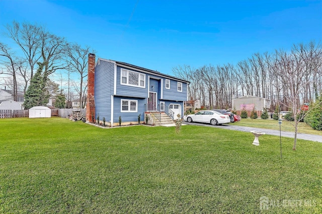 split foyer home featuring a chimney, aphalt driveway, an outbuilding, fence, and a storage unit