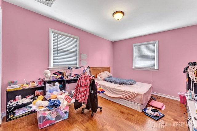 bedroom featuring visible vents, baseboards, and wood finished floors