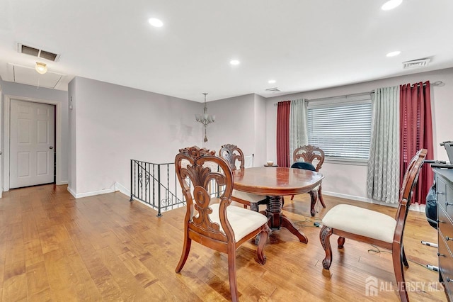 dining area featuring light wood finished floors, attic access, visible vents, and baseboards