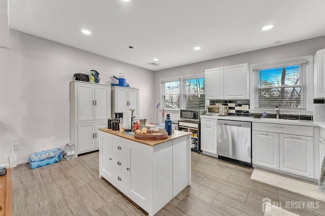 kitchen featuring white cabinets, a kitchen island, stainless steel appliances, and light countertops