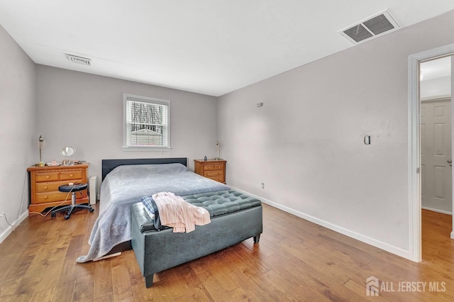 bedroom featuring hardwood / wood-style flooring, visible vents, and baseboards