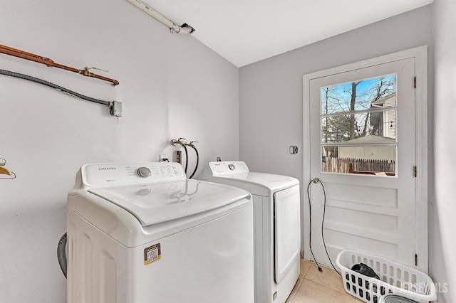 clothes washing area featuring laundry area, light tile patterned floors, and washer and clothes dryer